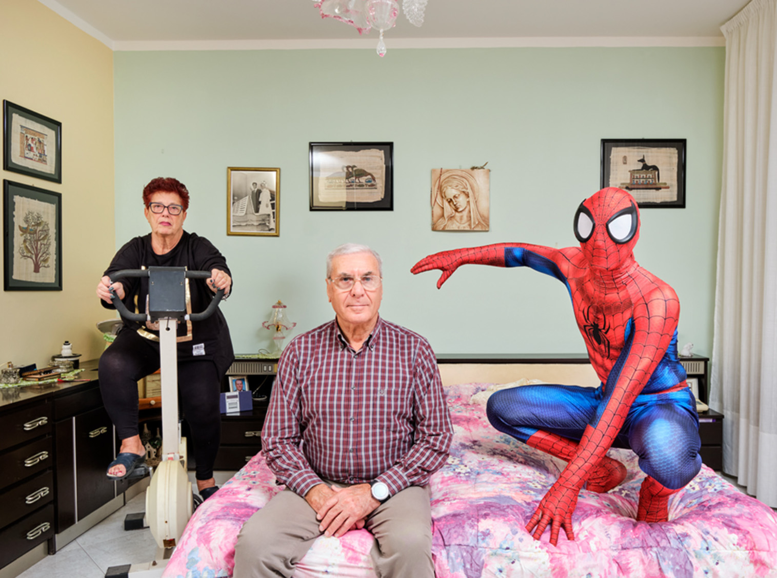 NICCOLO' RASTRELLI, They don't look like me. Manuel (28) poses with his grandparents in their bedroom in Livorno, Tuscany, Italy. Manuel works as a butcher and has been practicing cosplay since 2018; in the photo he plays Spider-Man, a Marvel Comics character.Manuel (28) poses with his grandparents in their bedroom in Livorno, Tuscany, Italy. Manuel works as a butcher and has been practicing cosplay since 2018; in the photo he plays Spider-Man, a Marvel Comics character.<br />
